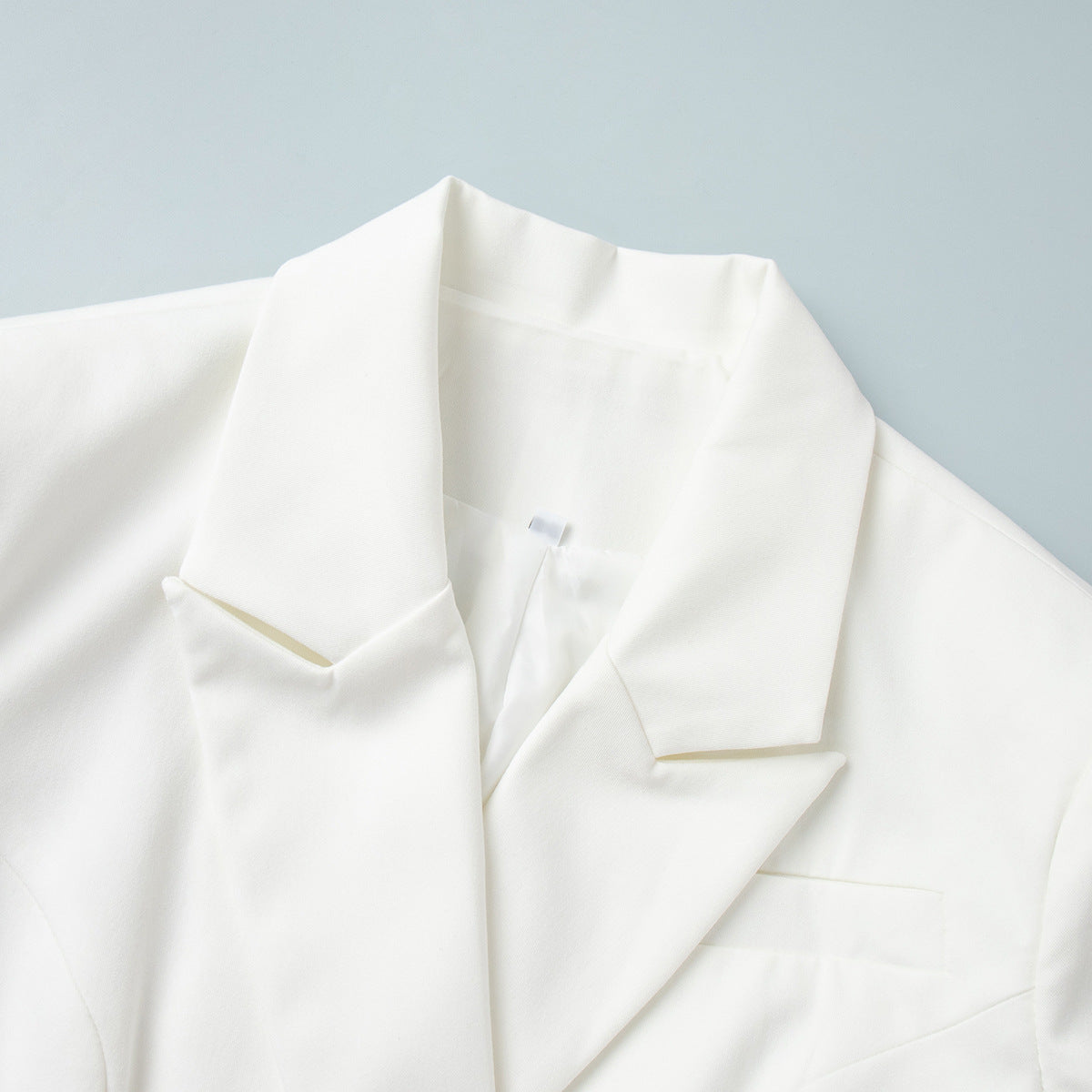 Close-up of tailored collar on women’s white blazer