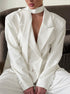 Woman seated wearing elegant white blazer suit