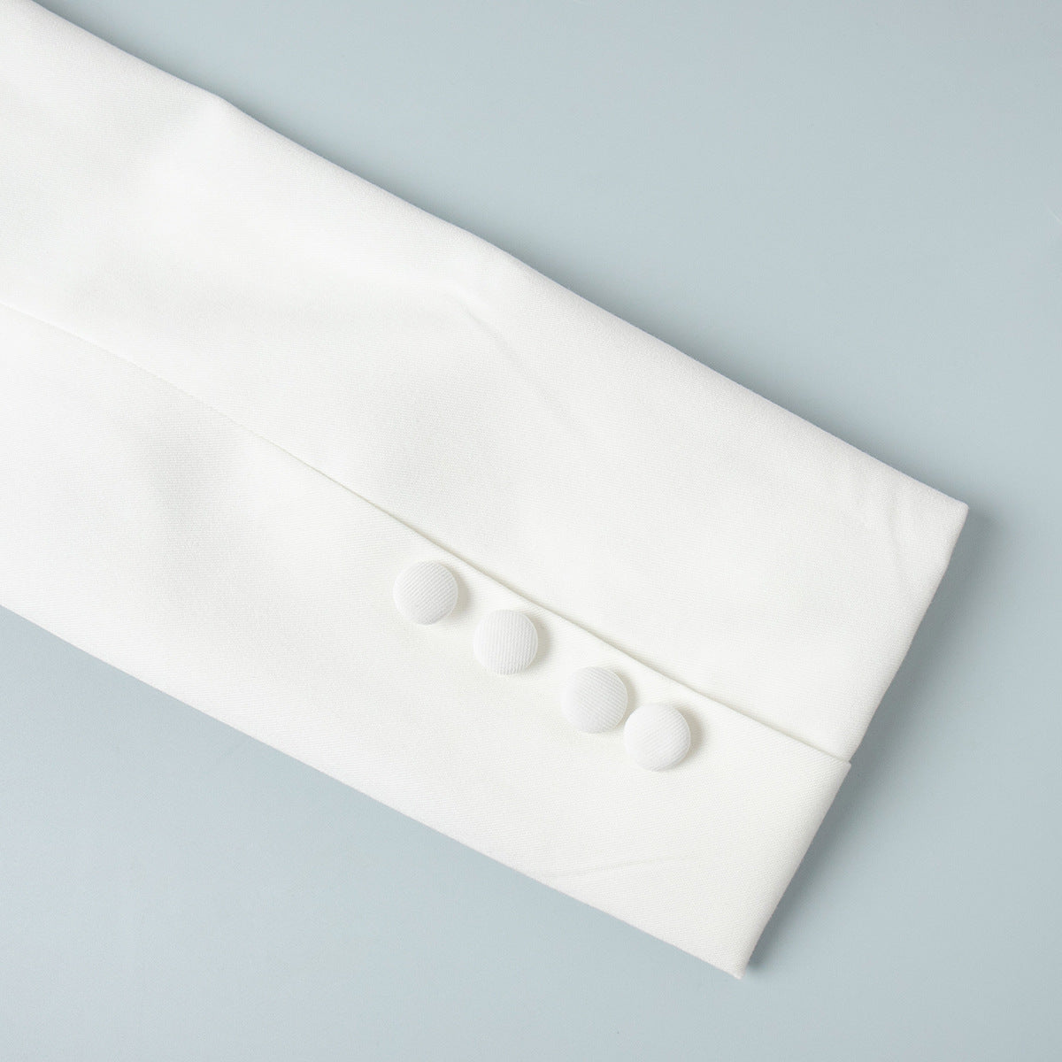 White blazer sleeve cuff with fabric-covered buttons
