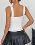 Back view of white structured corset top with wide straps, paired with black pleated leather skirt.