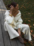 Sitting outdoors in white half zip sweater 2 piece set with wide pants
