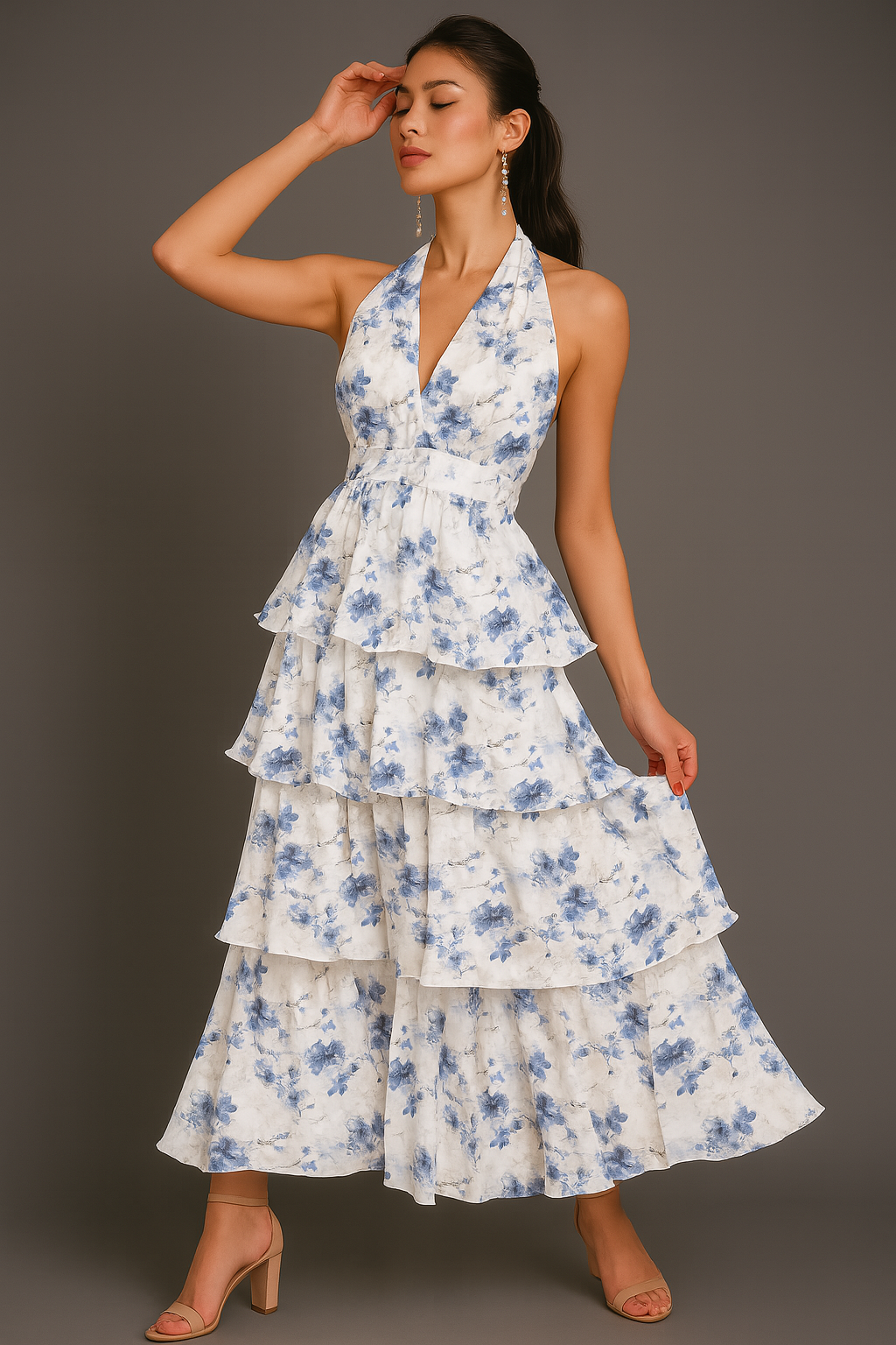 Woman wearing a ruffle white dress with blue floral patterns against a gray background