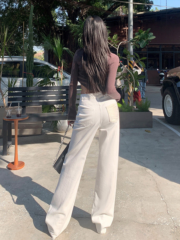 Back view of white straight-leg jeans with textured patch pocket and high-rise waist.