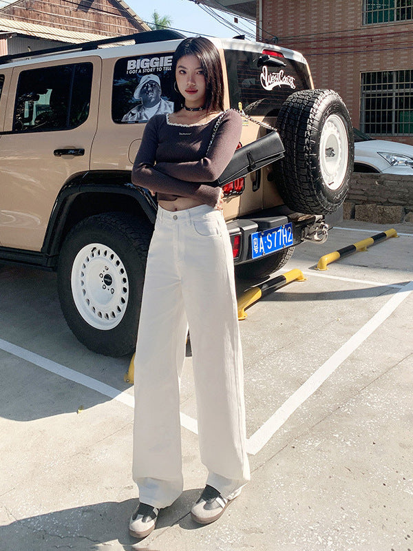 Woman wearing white high-waist straight-leg jeans with pockets in a minimalist spring outfit.