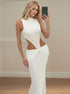 Sexy white hollow-out maxi dress with high neckline, side cut-outs, and draped waist shown in mirror front pose.