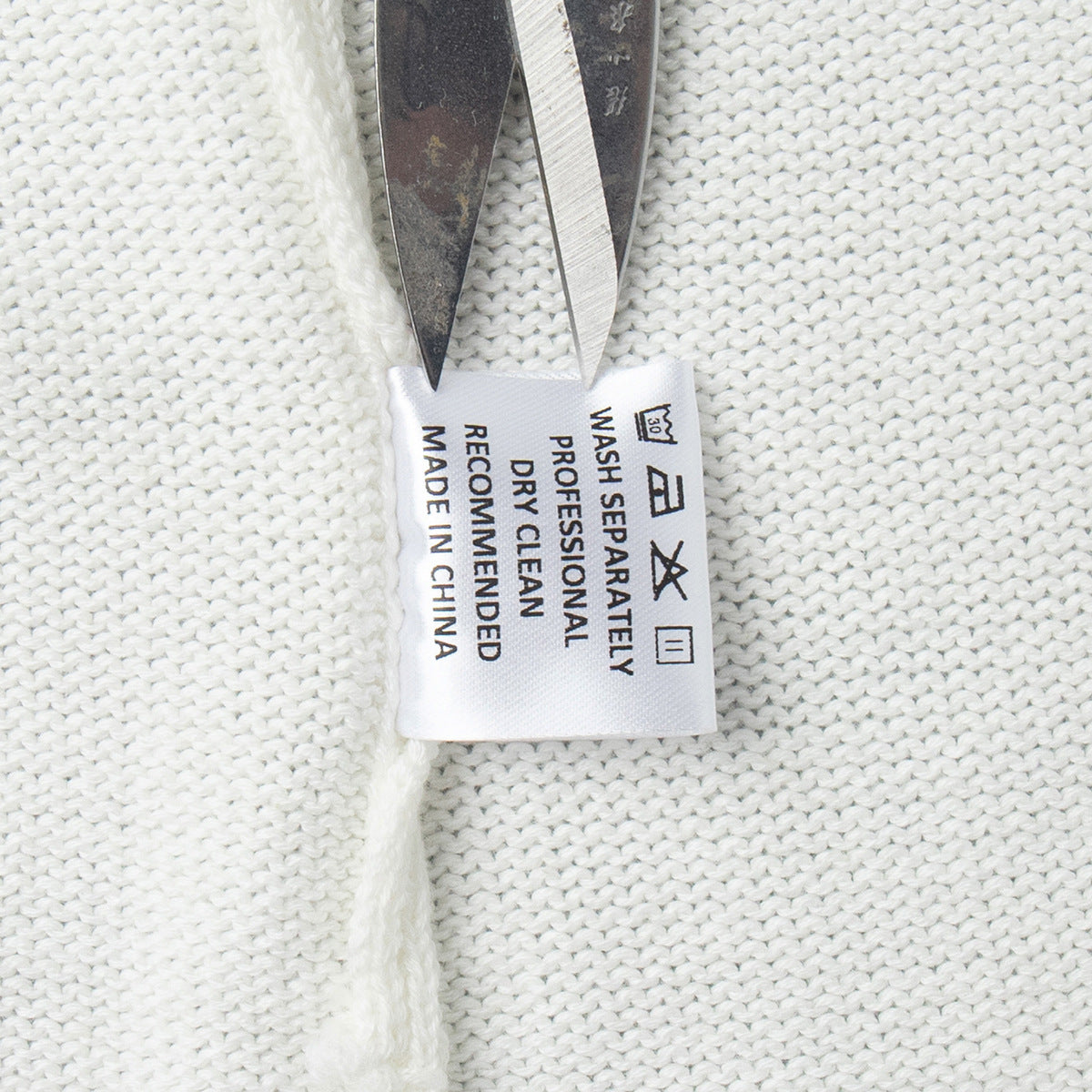Inner care label tag of white knit sweater with fabric information