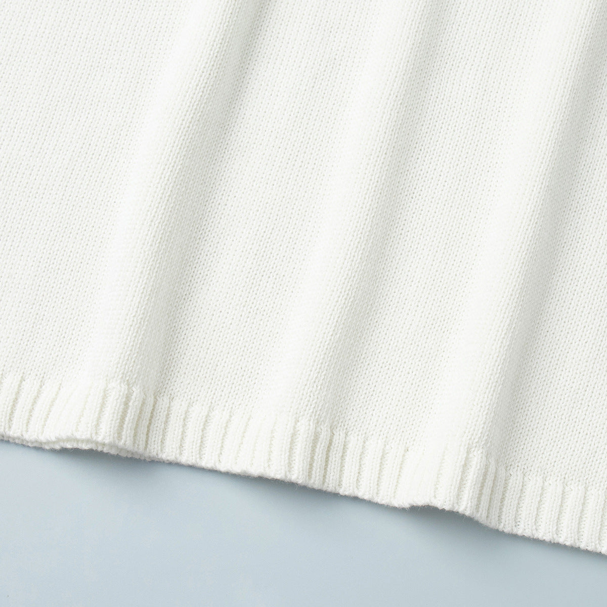 Hemline detail of white knit sweater with clean knit finish