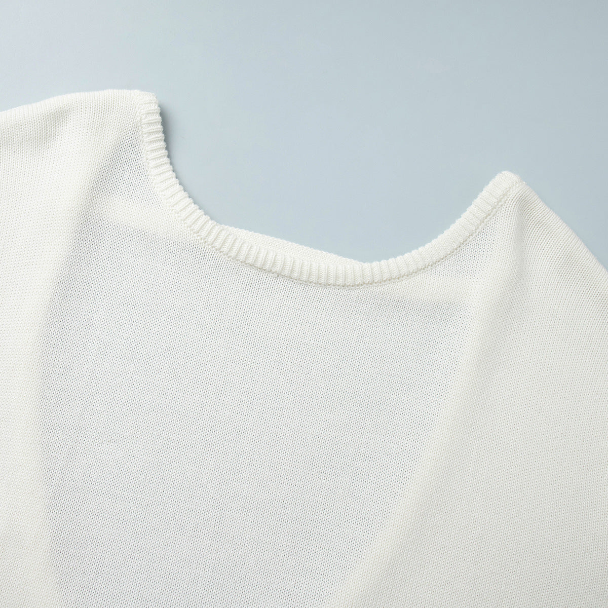 Close-up neckline of white knit sweater with clean stitch finish