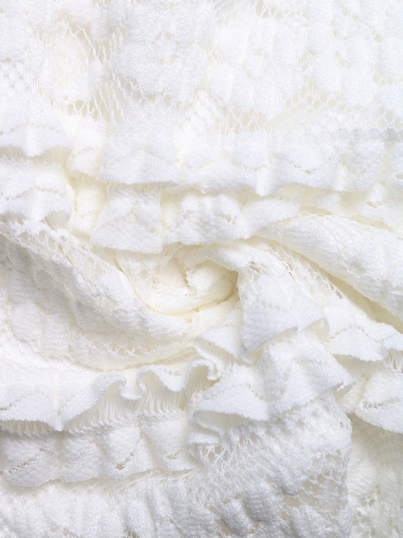 Macro shot of ruffled lace detailing on white corset top.