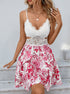 Smiling woman wears white floral sundress with lace top and flared skirt.