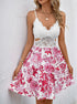 Woman wears sleeveless white lace sundress with red floral skirt and cutout waist.