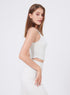 Side view of woman in white ruched athletic tank top and matching high-waisted leggings.