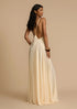 Woman wearing a white deep V vacation maxi dress with lace waist and flowing hem against a beige background