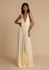 Woman wearing a white deep V vacation maxi dress with lace waist and flowing hem against a beige background