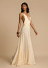 Woman wearing a white deep V vacation maxi dress with lace waist and flowing hem on a beige background