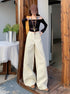 Front view of white wide-leg jeans paired with black long-sleeve top and gold chain necklace.