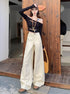 Model in white wide-leg jeans and cropped black top standing on rustic wood patio.