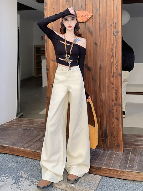 Model in white wide-leg jeans and cropped black top standing on rustic wood patio.