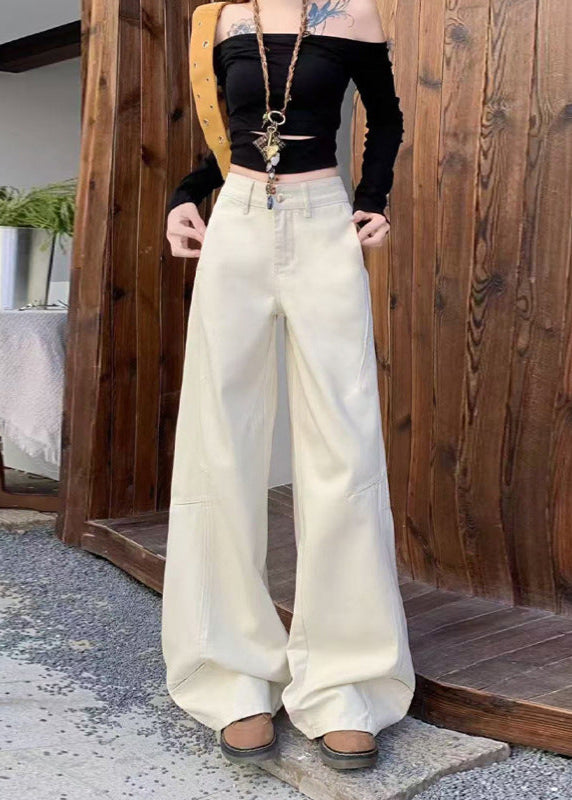 White wide-leg jeans styled with off-shoulder black crop top and tan accessories outdoors.