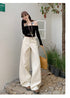 White curved hem wide-leg jeans styled with black off-shoulder crop top and cap.