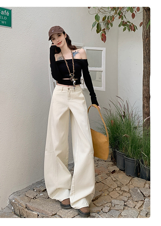 White curved hem wide-leg jeans styled with black off-shoulder crop top and cap.