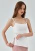 Woman adjusting white yoga tank top with ruched side.