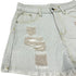 Close-up of distressed detailing on light wash denim shorts showing frayed fabric and stitching.