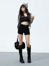 Woman in black high-waisted shorts with striped hoodie and knee-high boots holding iced coffee