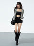 Woman walking in black high-waisted shorts, bandeau top, and striped jacket
