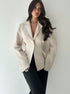 women’s beige blazer, slim fit one-button lapel, front 3/4 with black trousers