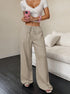 Person wearing a white top and khaki wide-leg pants holding a pink phone.