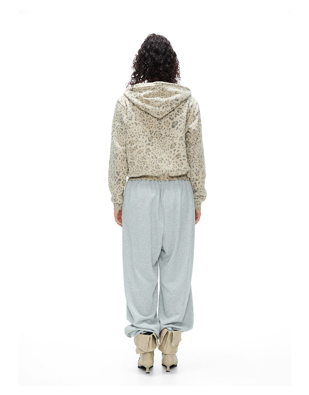 Back full body view of a model wearing a leopard print zip hoodie jacket with hood down.