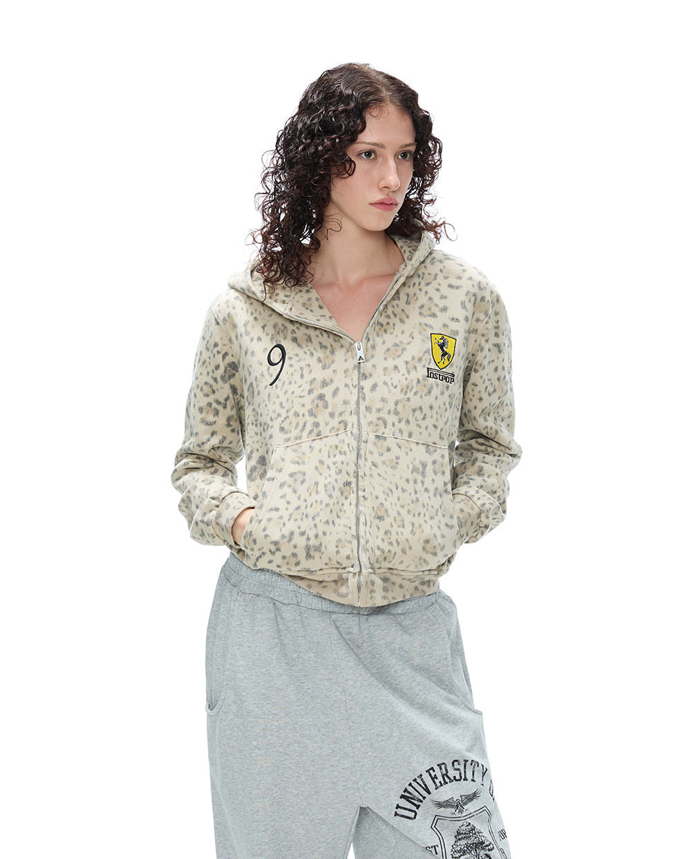 Front half-length shot of a model wearing a leopard print zip-up hoodie jacket with hands in pocket.