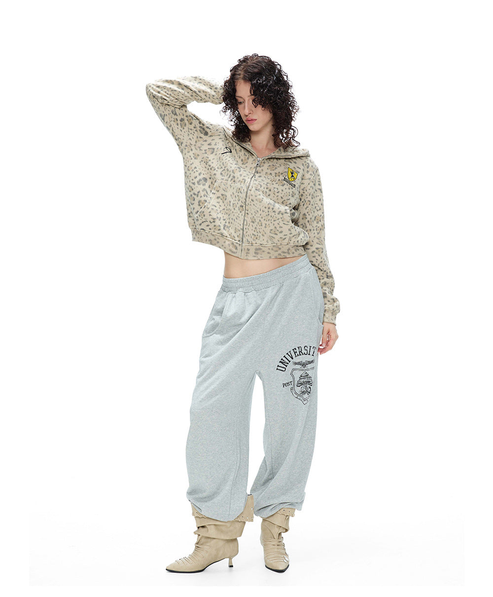 Full body shot of a model posing in a leopard zip-up hoodie jacket, slouchy trousers, and boots.