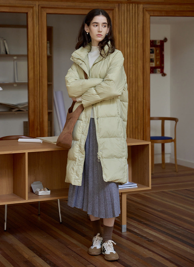 Women’s light green long down puffer coat styled with pleated skirt and sneakers
