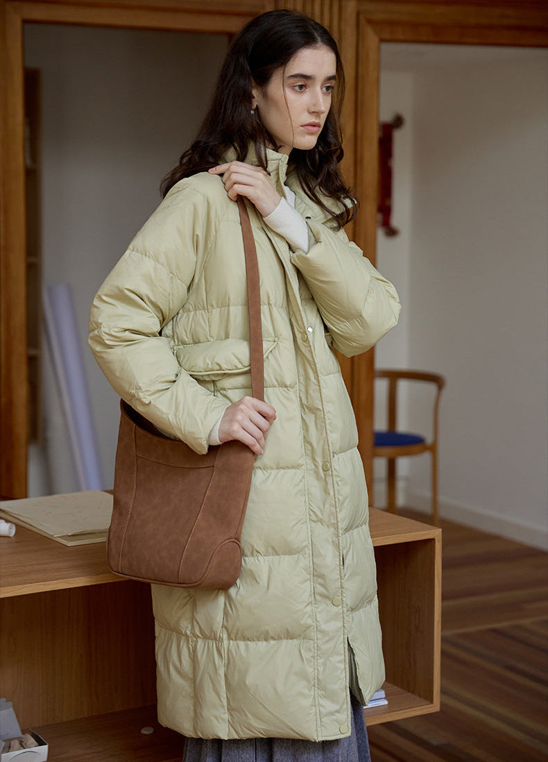 Light green long puffer coat for women with brown shoulder bag and high collar