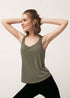 Woman stretching in an army green racerback tank top and black leggings.