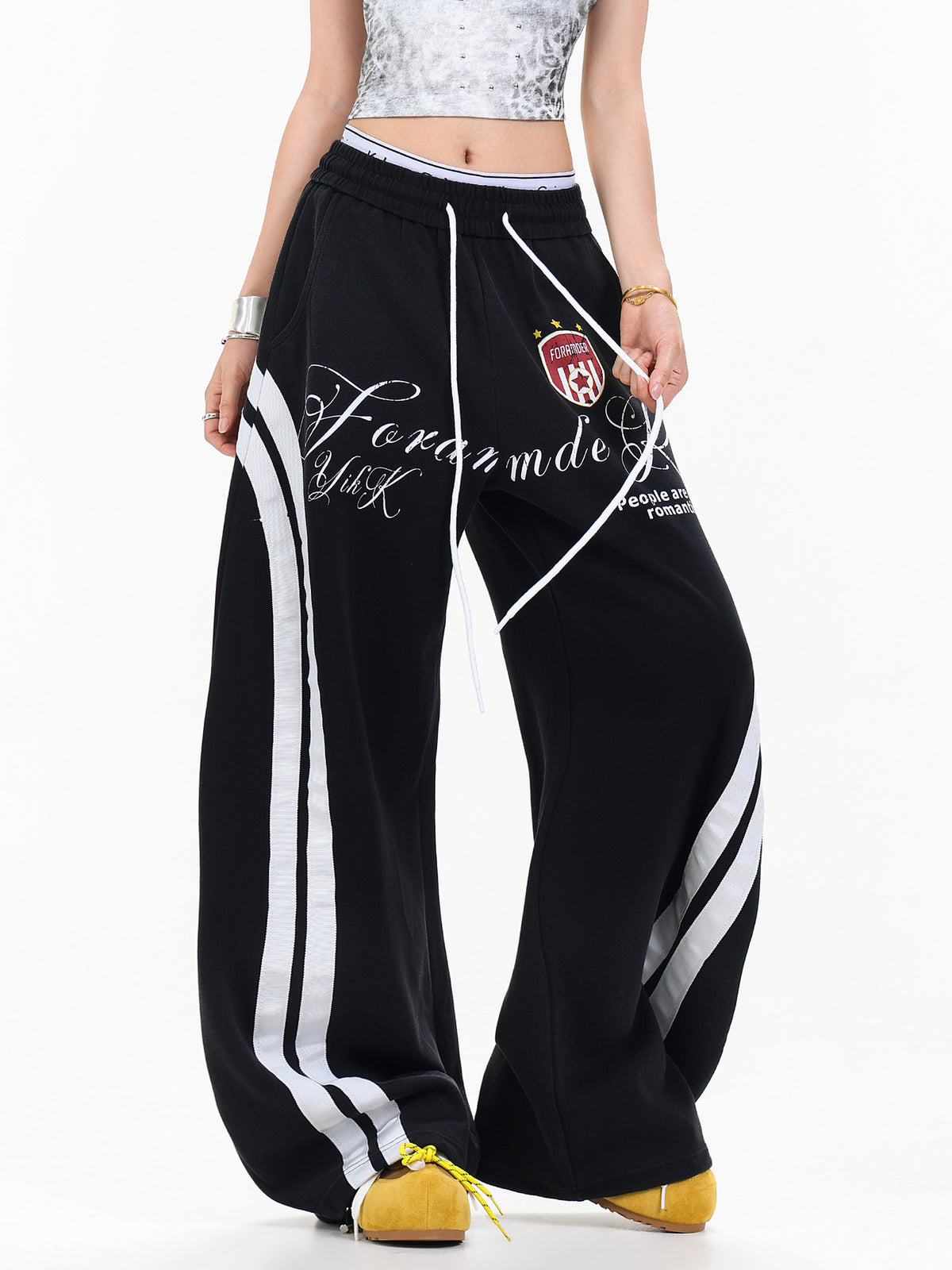 Three-quarter view of female model styled in black side stripe curved leg lounge pants with white drawstring.