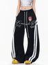 Full length front view of black graphic print wide leg sweatpants paired with crop top and sneakers.