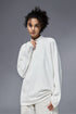 Woman wearing white half zip long sleeve t shirt against a gray background