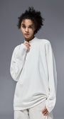 Woman wearing white half zip long sleeve t shirt against a gray background