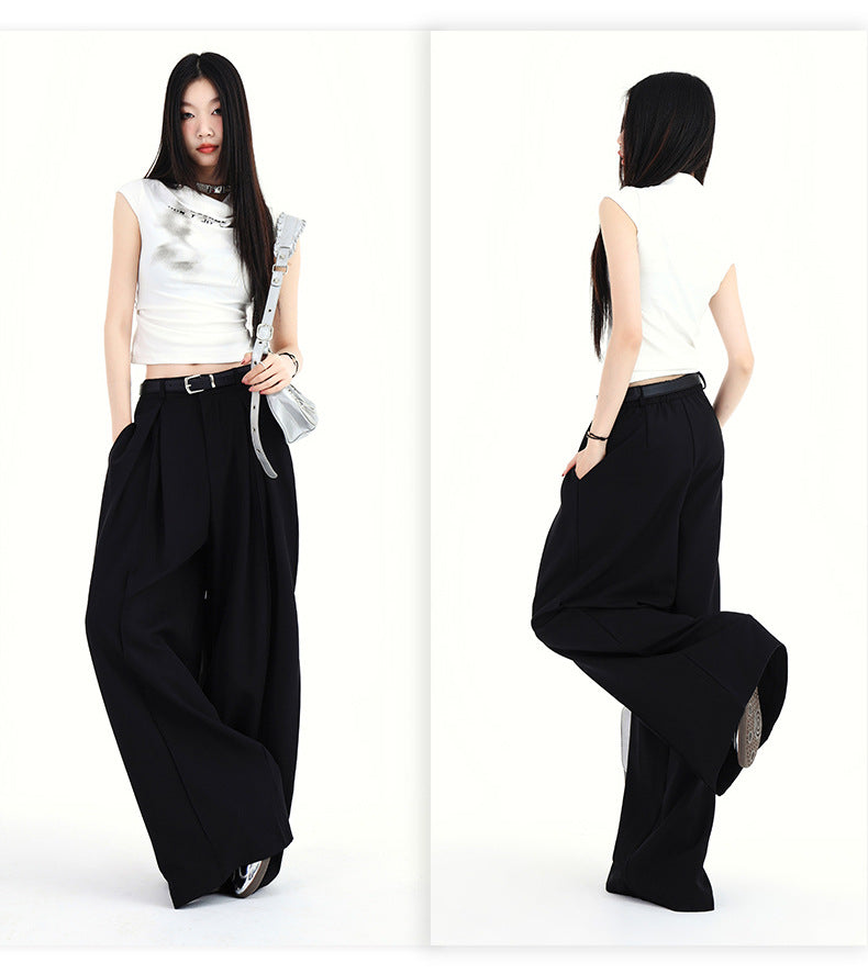 Woman modeling black pleated wide-leg pants with high waist fit.
