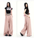 Blush pink pleated pants styled with black crop top, shown front and side.