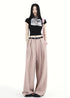 Woman styling blush pink wide-leg trousers with pleats and belt.