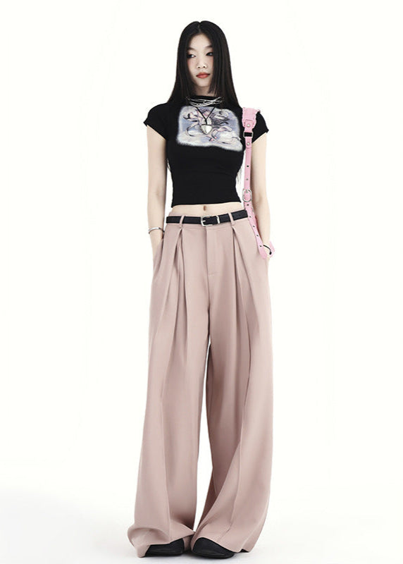 Woman styling blush pink wide-leg trousers with pleats and belt.