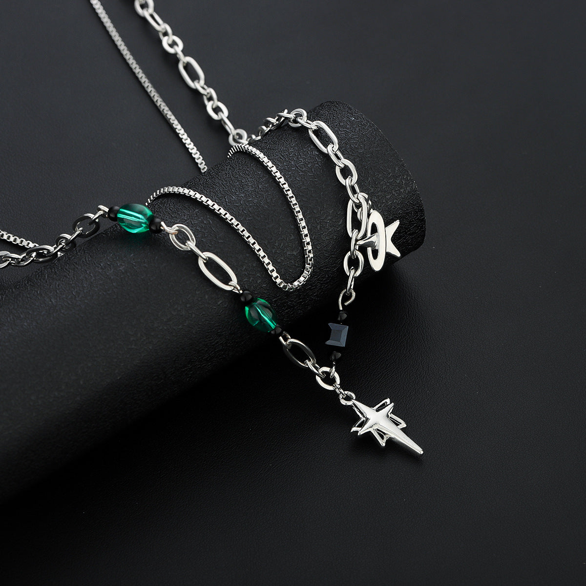 Close-up of silver double-chain necklace with green beads and dangling star charm.