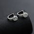 White marble-pattern stud earrings on textured black roll.