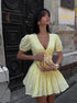 Woman in a yellow dress standing on a street with a textured wall background