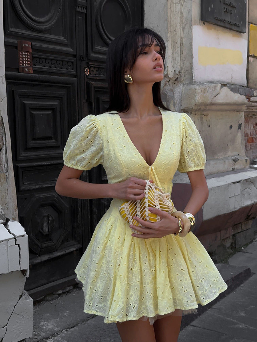 Woman in a yellow dress standing on a street with a textured wall background