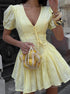 Woman wearing a yellow dress holding a matching handbag.